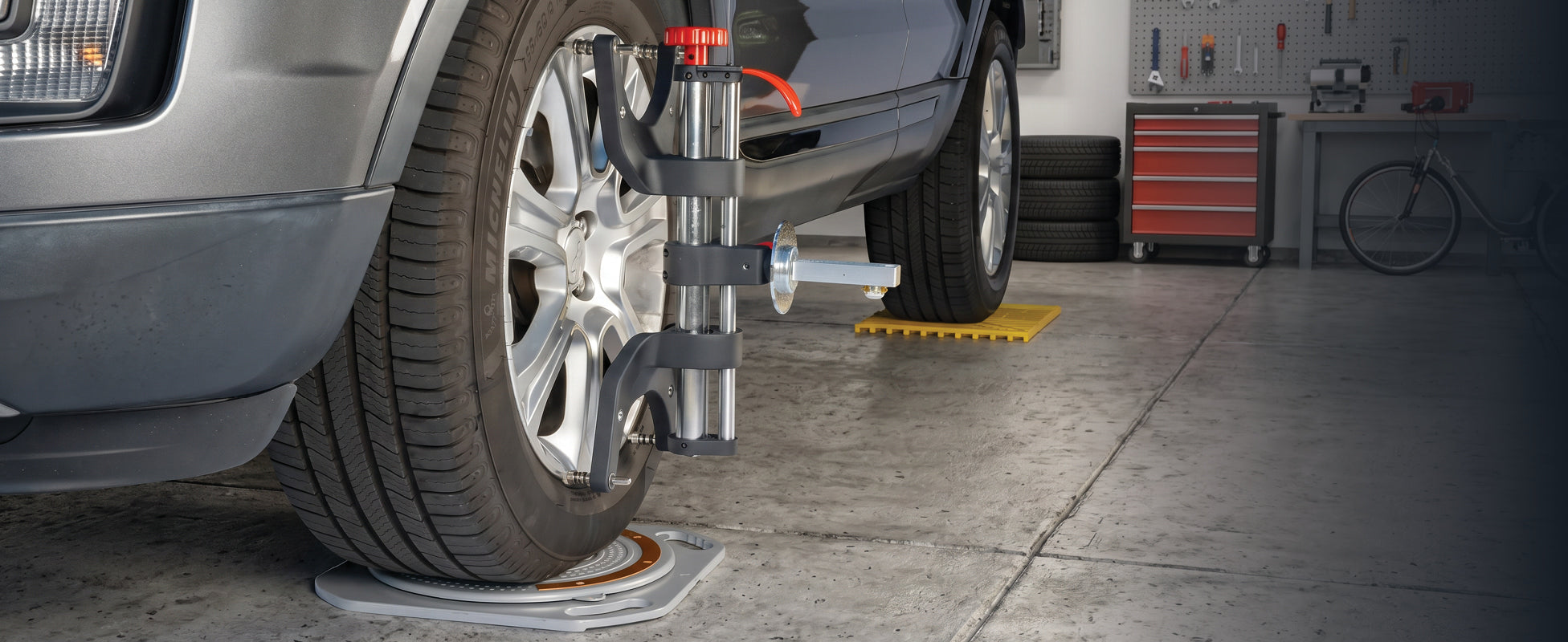 AutoSolo ASCGAL magnetic camber caster gauge mounted on a wheel hub in a home garage