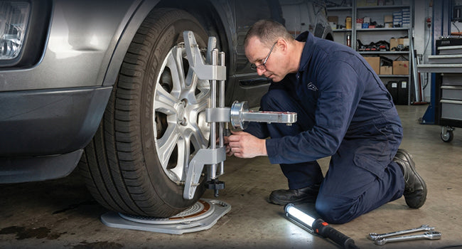 Wheel clamp and alignment gauge mounted on a front wheel while the setup is worked at the car
