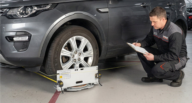 Toe plate set against a tire with the string line and tape measures run alongside the car